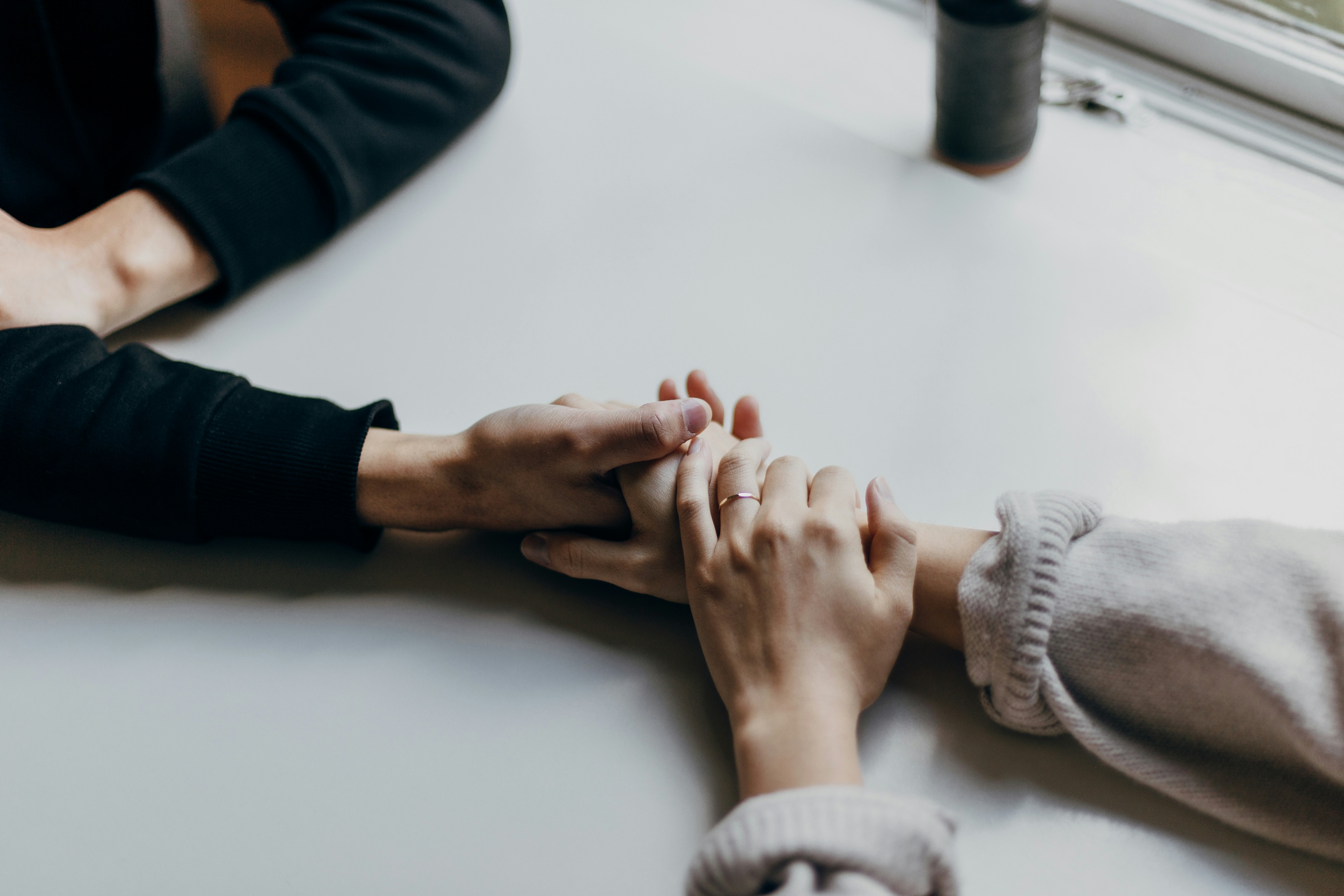 One person holding another's hands across a table
